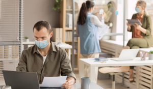 Title image for What is the Employee Retention Credit? showing three co-workers laboring in the office while using face masks.